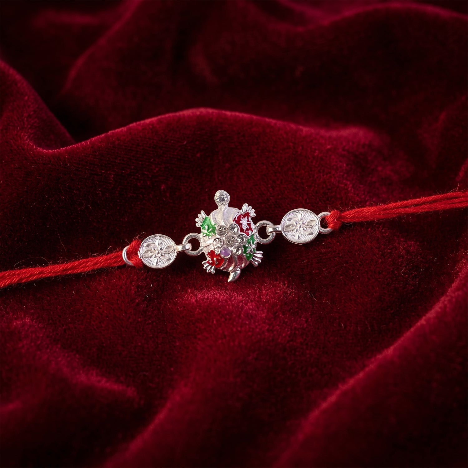 Silver floral rakhi tied on soft thread with colorful accents