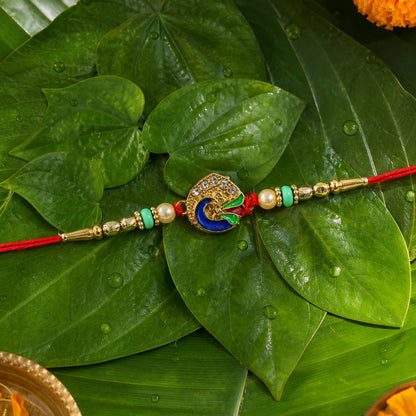Peacock rakhi tied with red thread with pearl beads