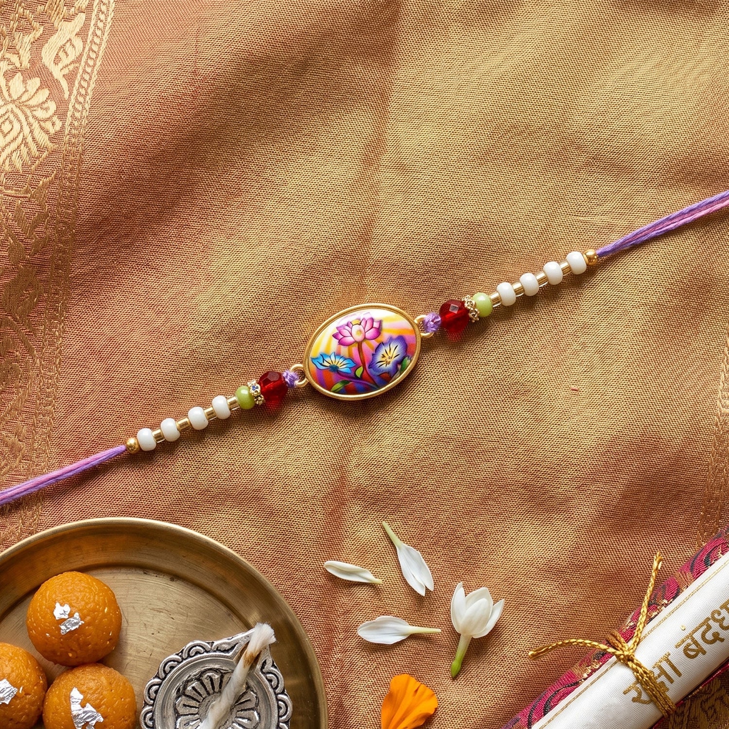 Floral Designer Rakhi displayed flat with purple thread