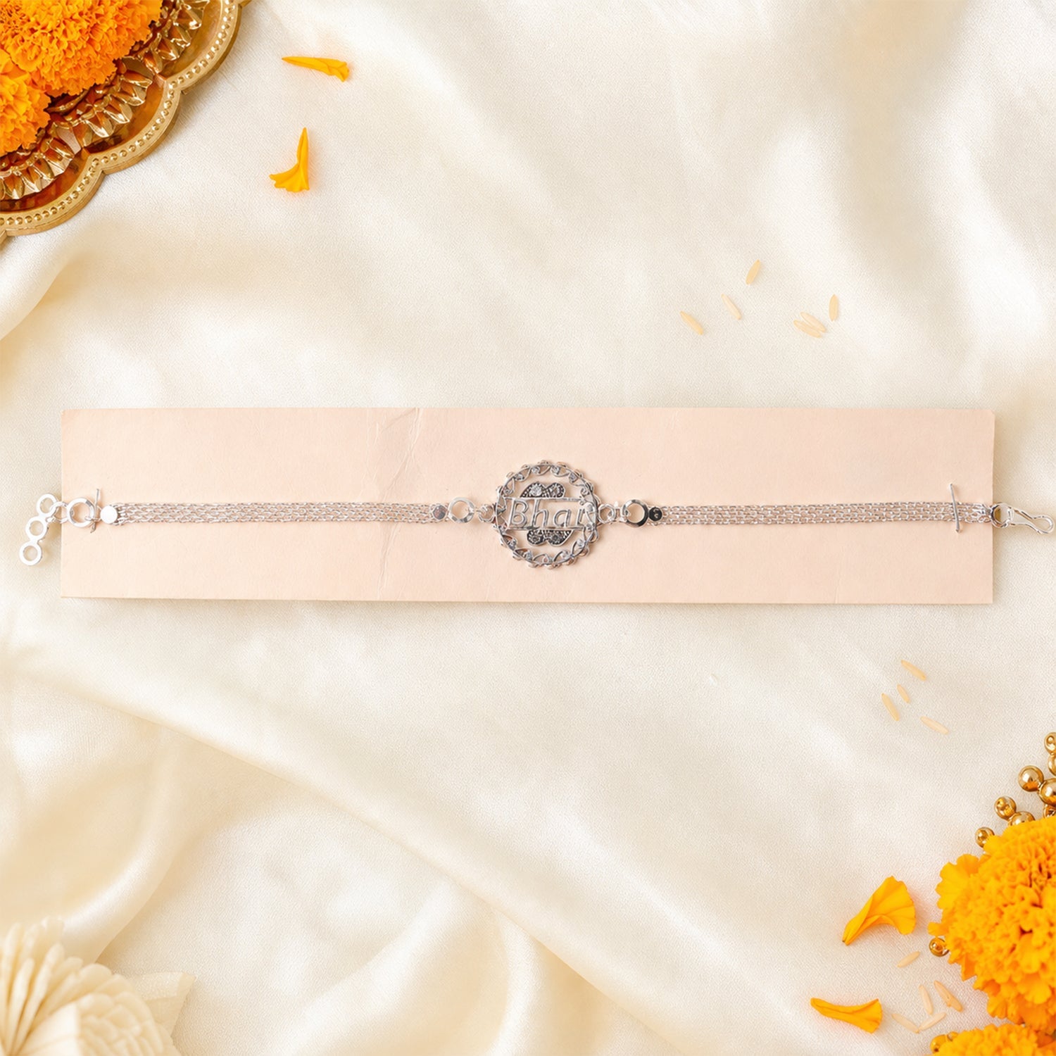 Silver rakhi laid out showing chain and design