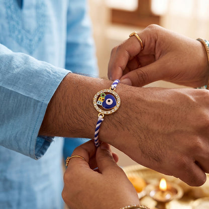 Close-up of blue evil eye and decorative beads on fancy dori rakhi