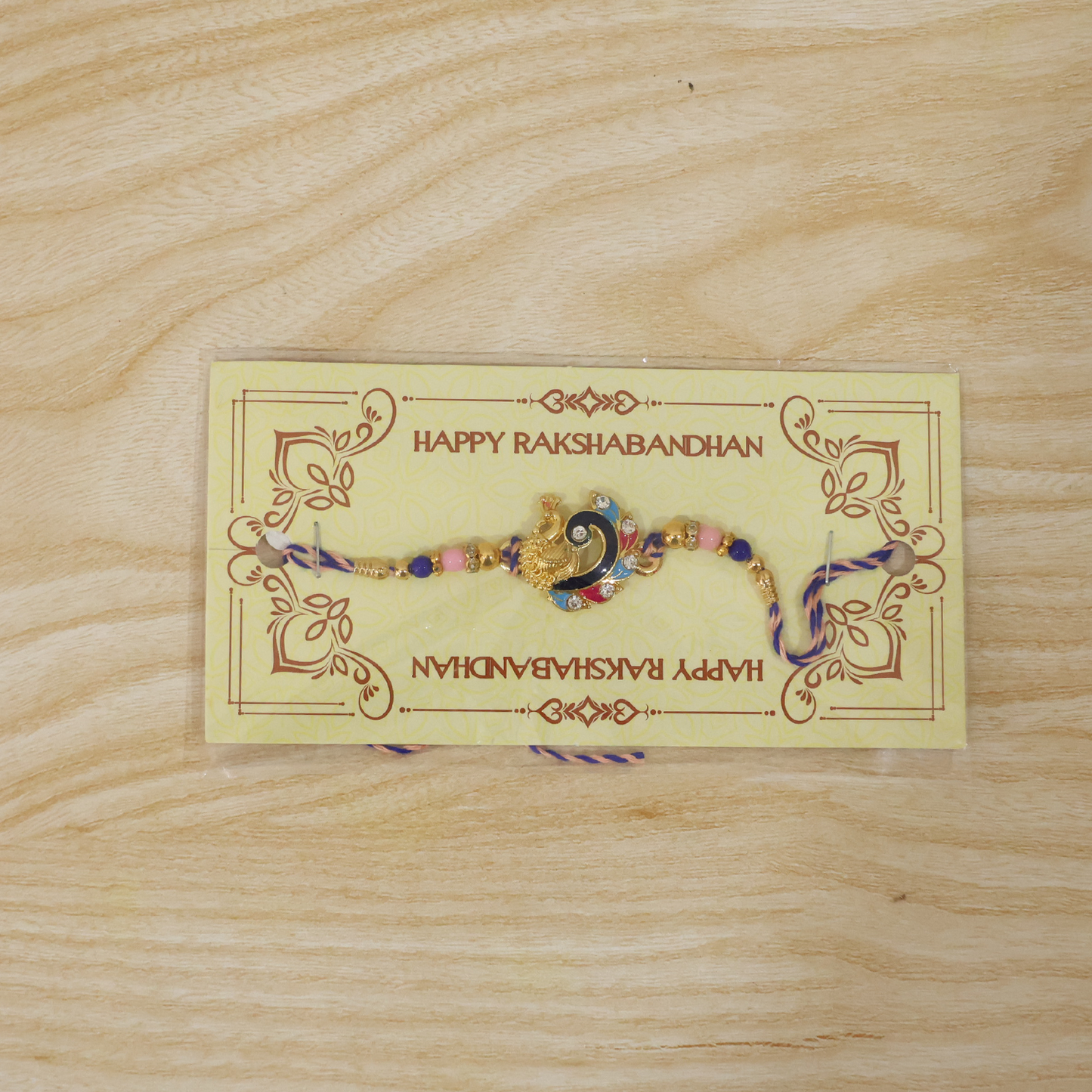 Side angle of blue enamel peacock charm rakhi with beads