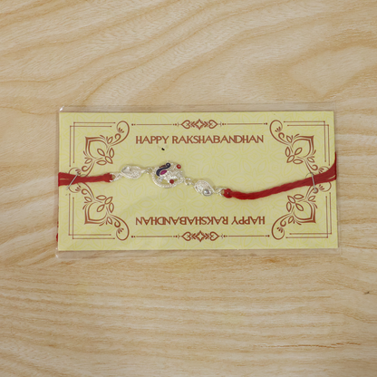 Silver peacock charm rakhi with vibrant red thread