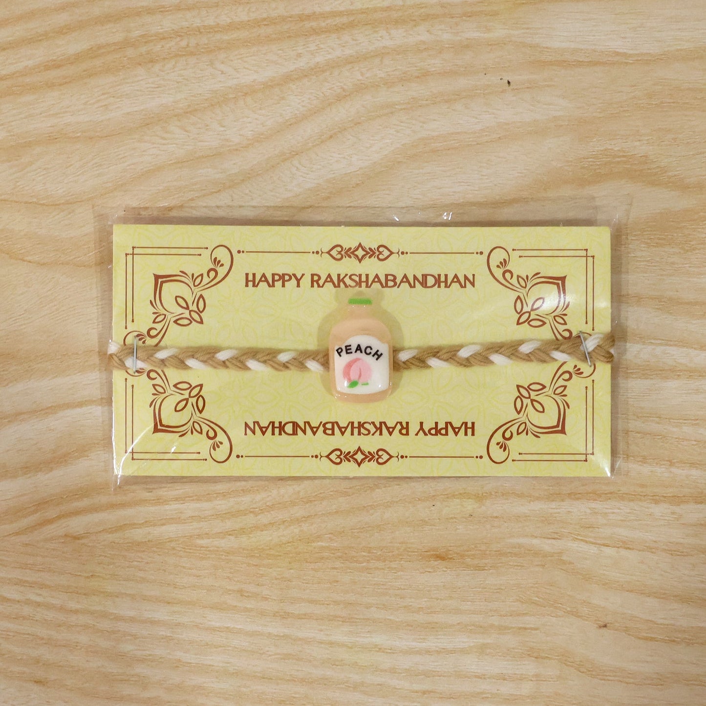 Decorative peach bottle charm on rakhi string
