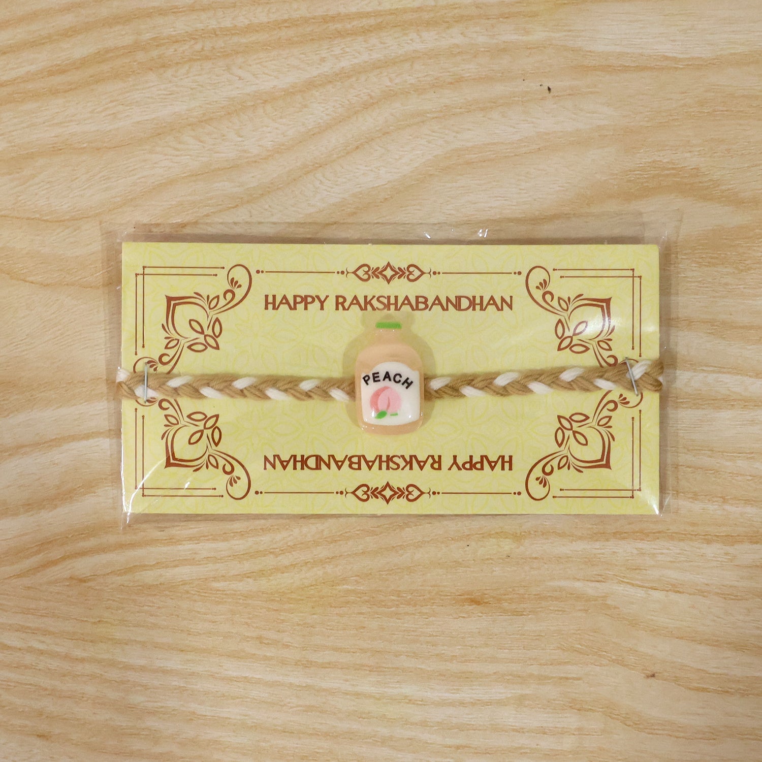 Decorative peach bottle charm on rakhi string