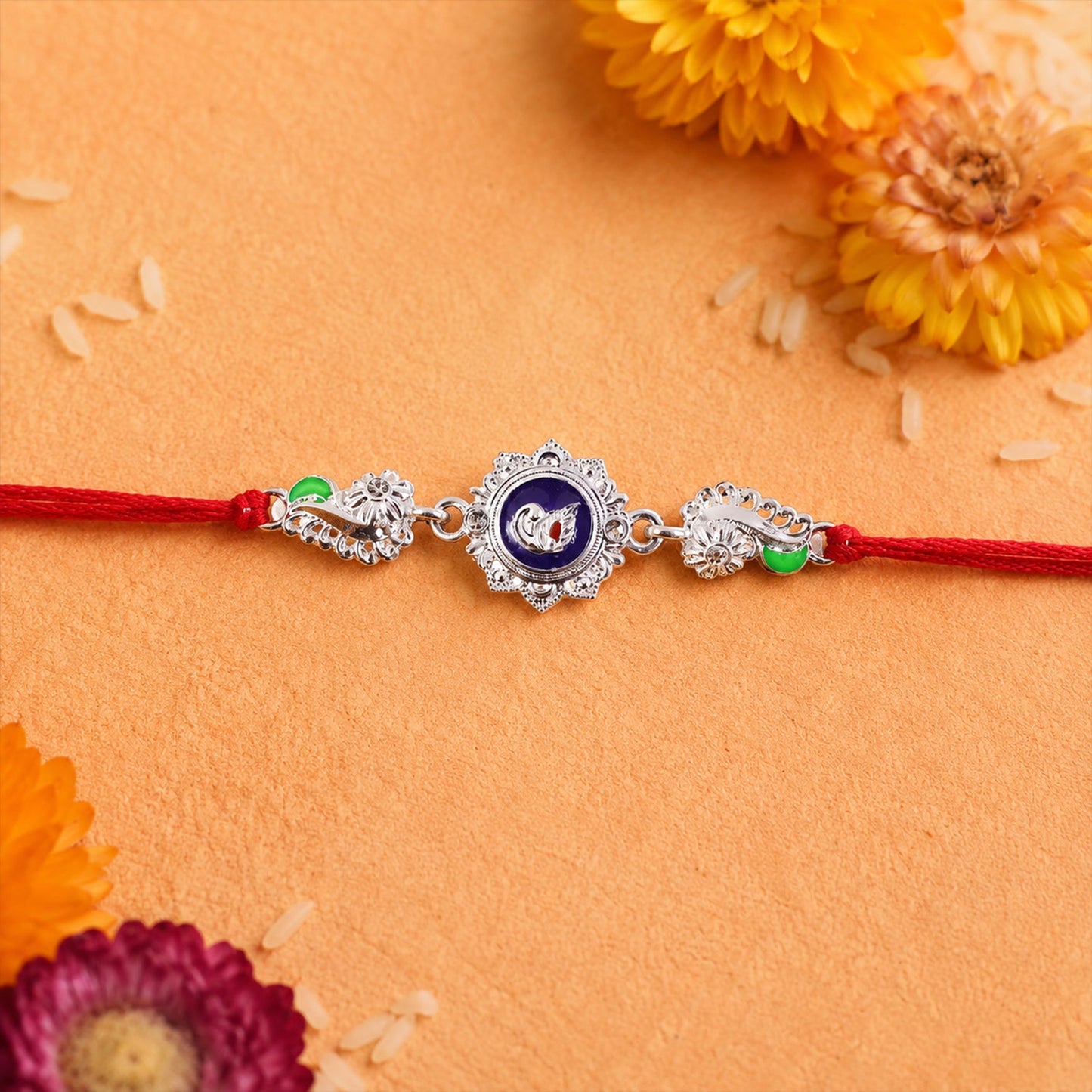 Close-up of silver charm on red thread rakhi