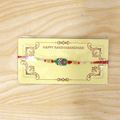 Close-up of handmade beaded rakhi with Mor Pankh charm