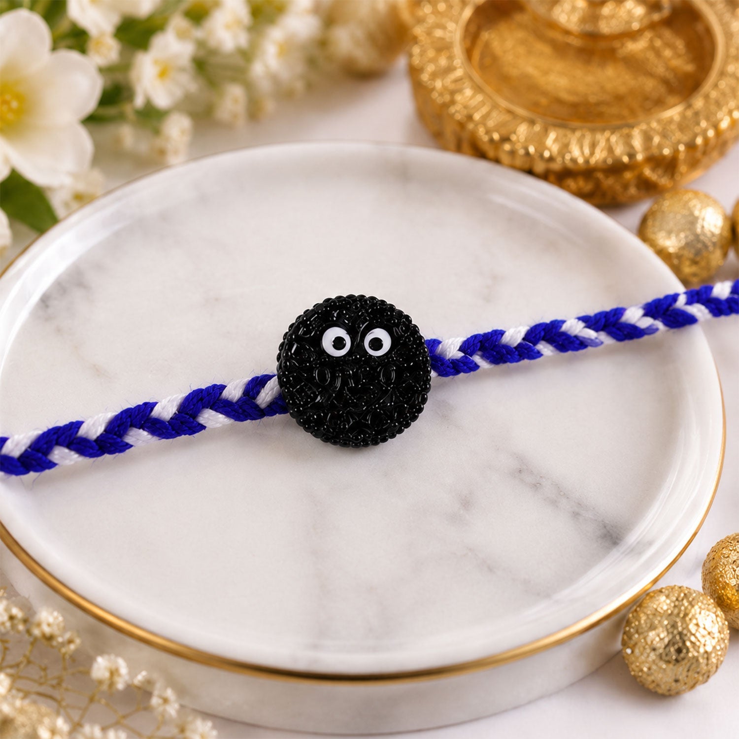 Close-up of cookie eyes charm on braided thread rakhi