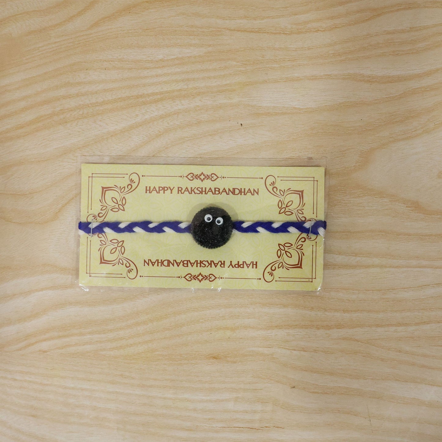 Full view of Funny Cookie Eyes Braided Thread Rakhi on white background
