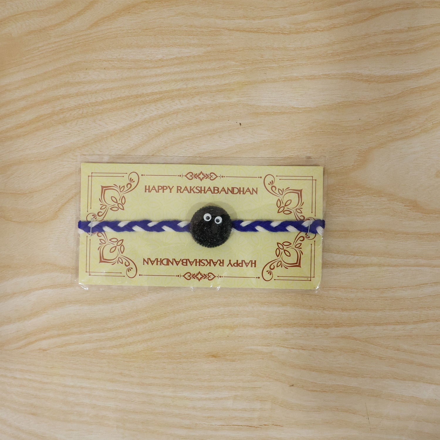 Full view of Funny Cookie Eyes Braided Thread Rakhi on white background