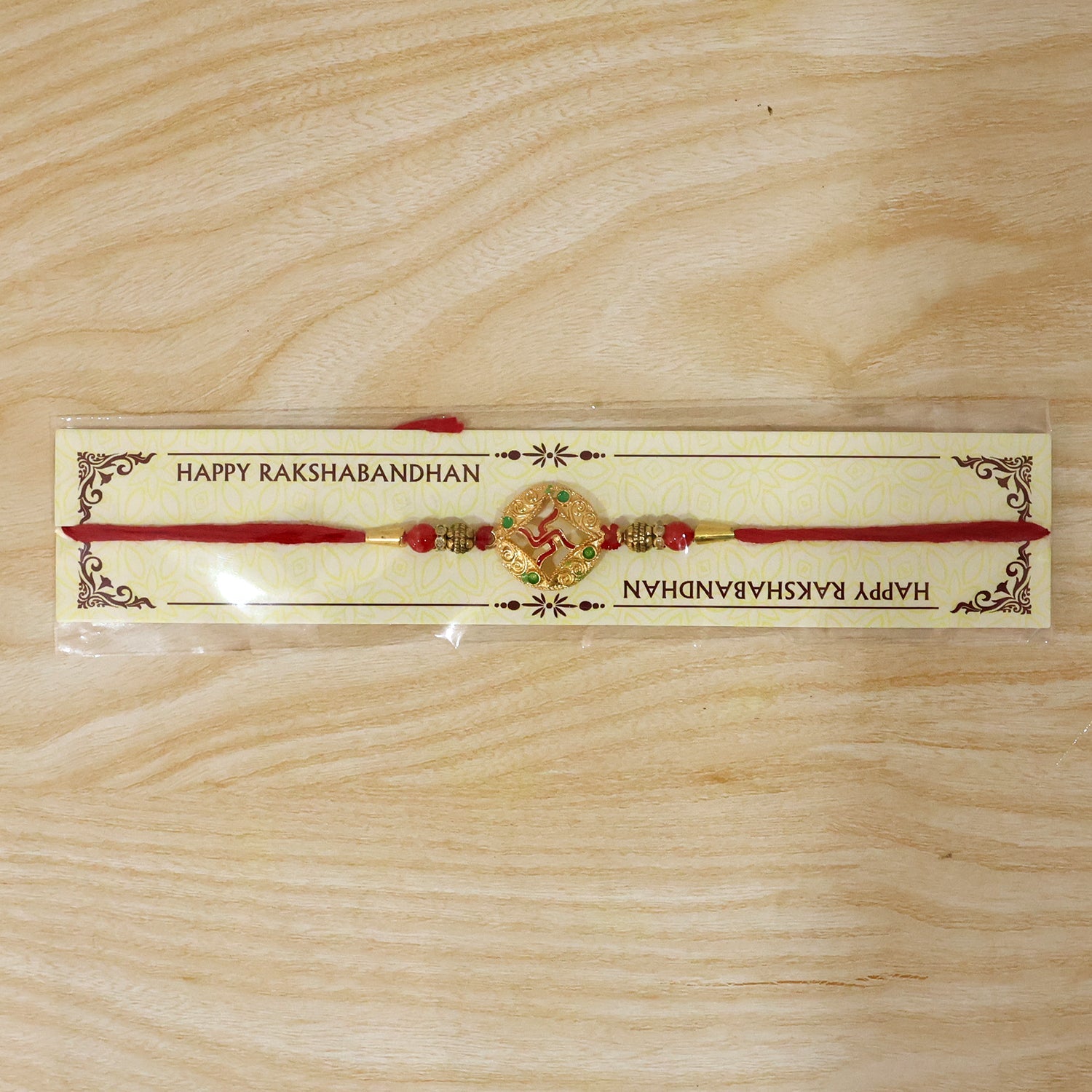 Festive golden swastik designer rakhi with beads on white background
