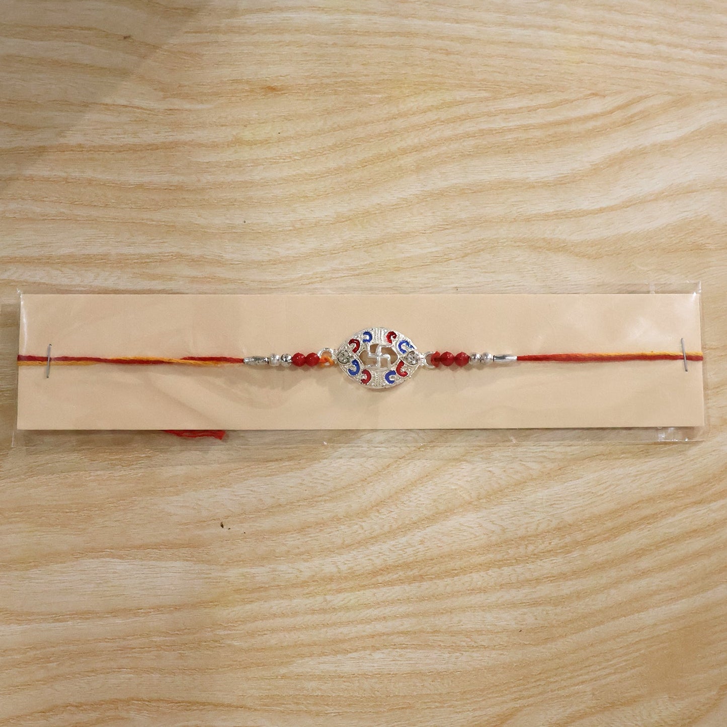Silver Swastik Meena Oval Charm Rakhi with beads on festive background