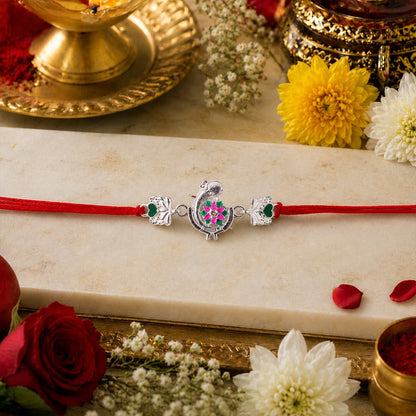 Top view of Silver Peacock Flower Heart Rakhi with dori