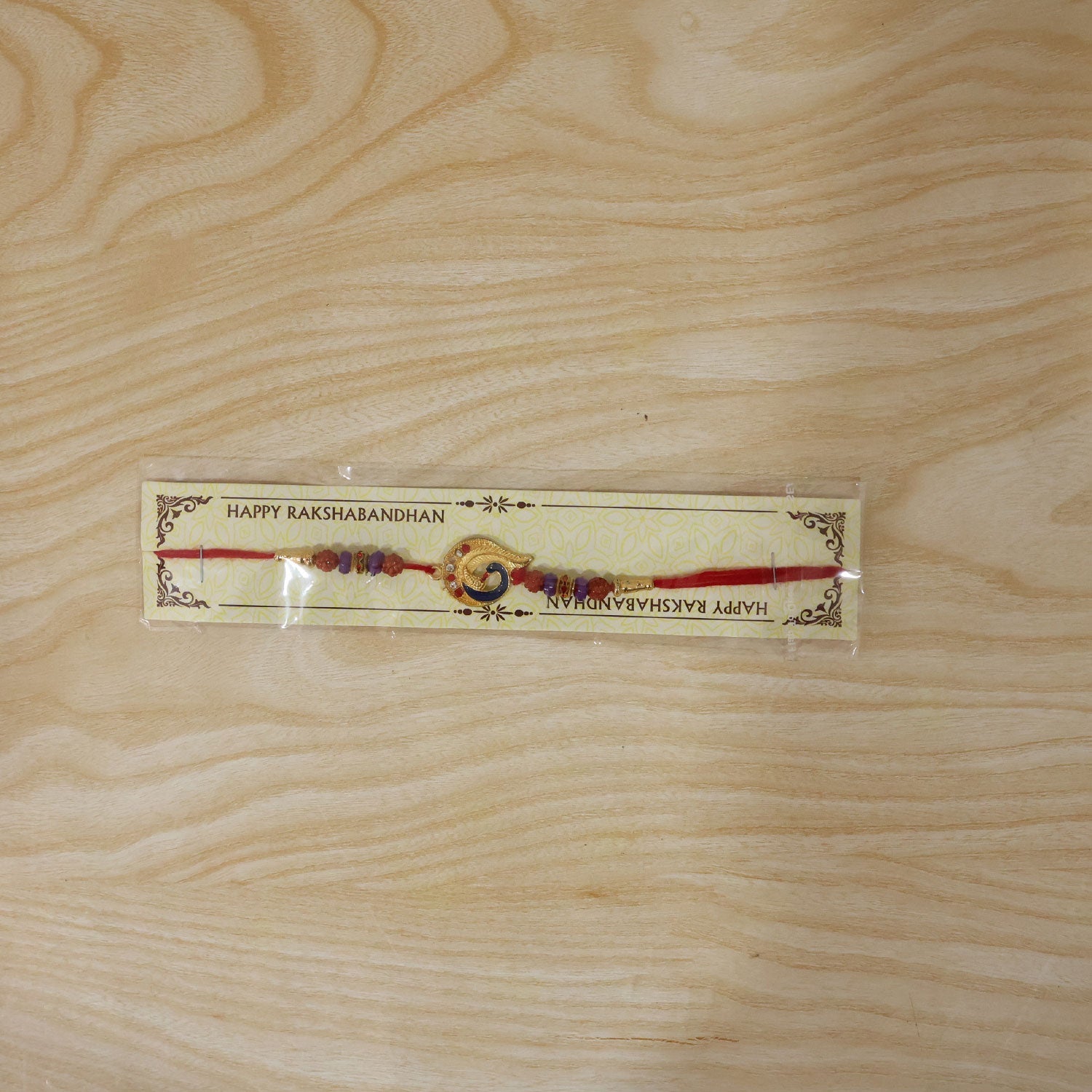 Detailed shot of decorative beads on Golden Mor Feather Rakhi