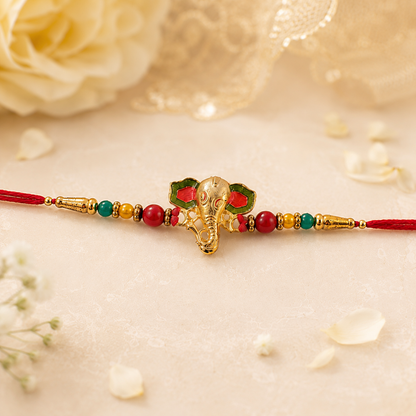 Golden Ganesha charm and thread on Rakhi showcasing intricate design