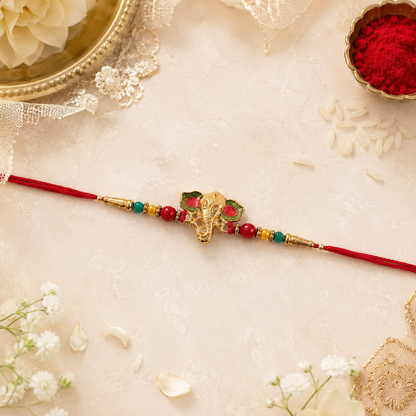 Close-up of golden Ganesha charm on rakhi with beads