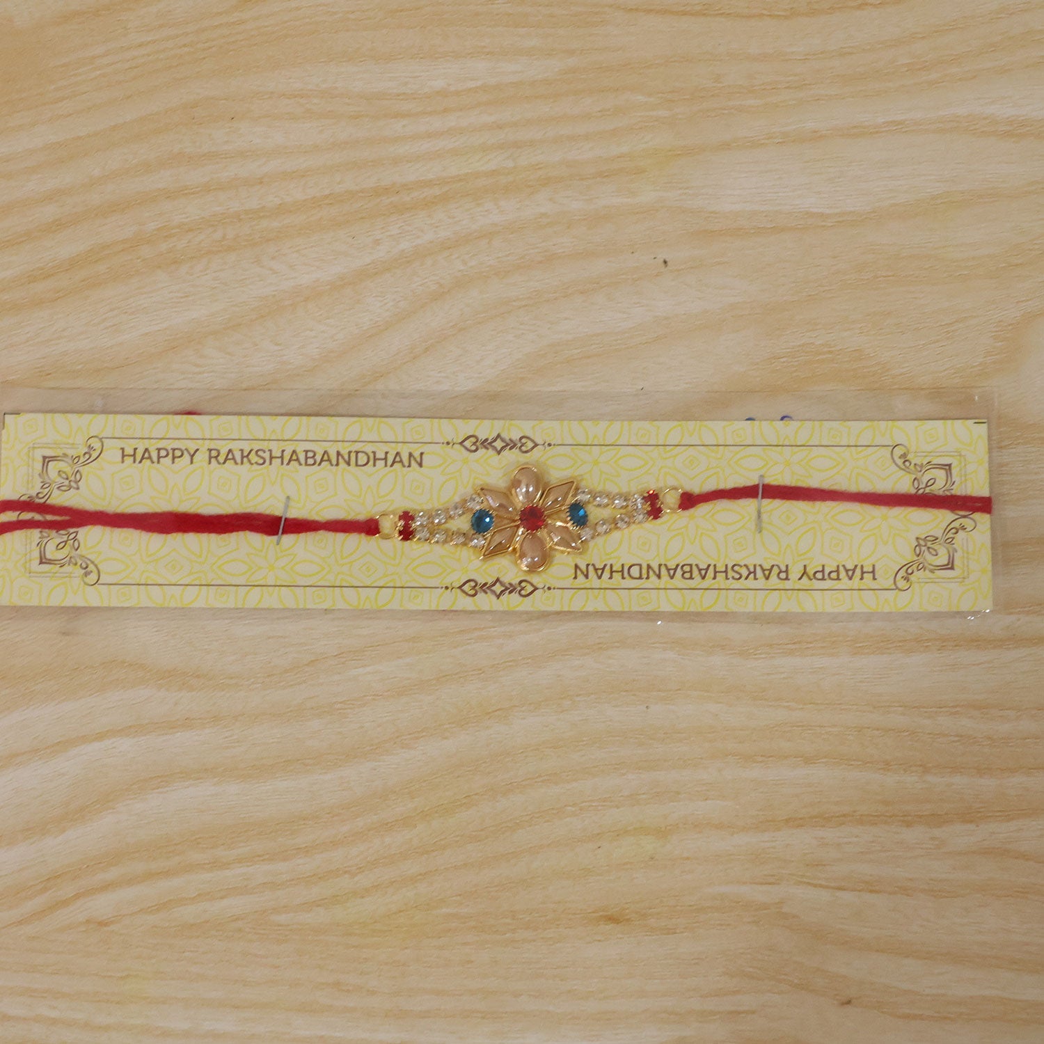 Designer Pearl Flower Rakhi with Blue & Red Stones for Brother