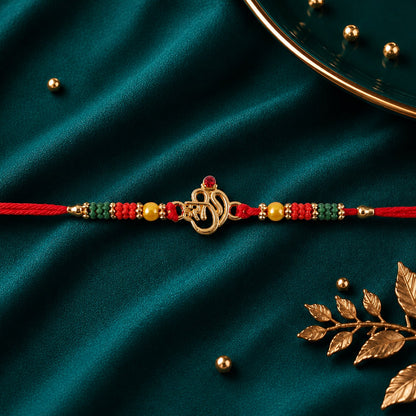 Golden Om (?) Rakhi with Red & Green Crystal Beads