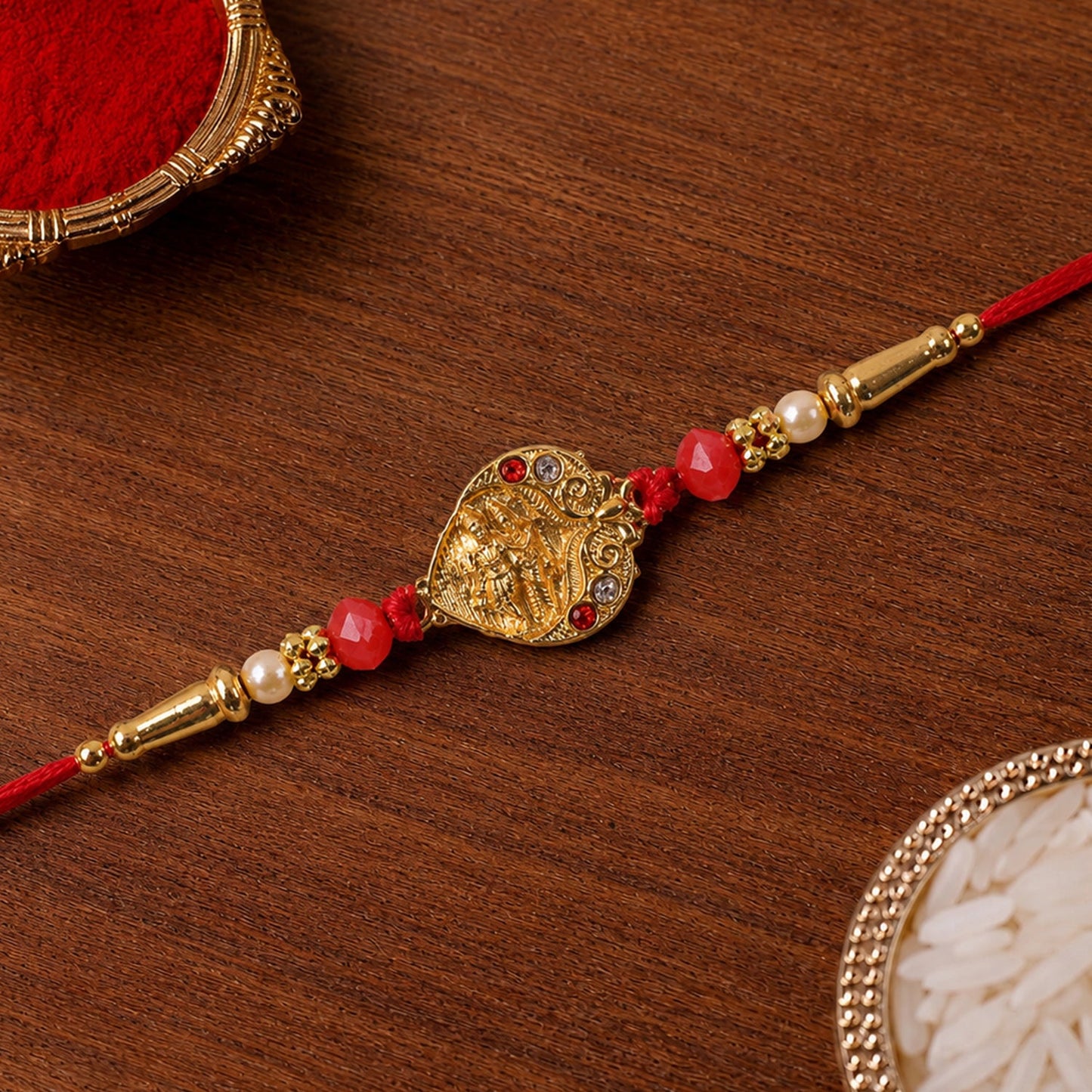 Golden Ganesha Oval Rakhi with Red Crystal Beads