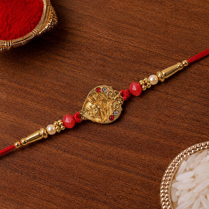 Golden Ganesha Oval Rakhi with Red Crystal Beads