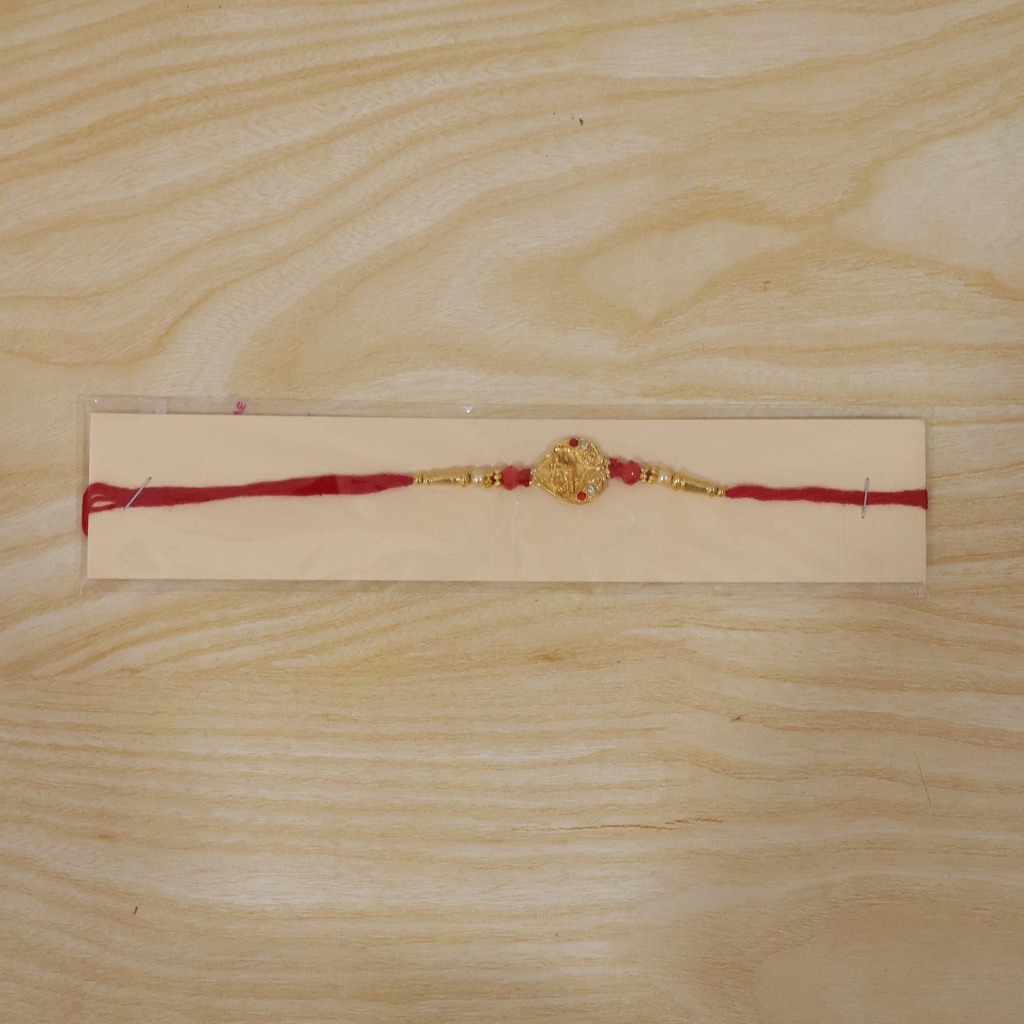 Golden Ganesha Oval Rakhi with Red Crystal Beads