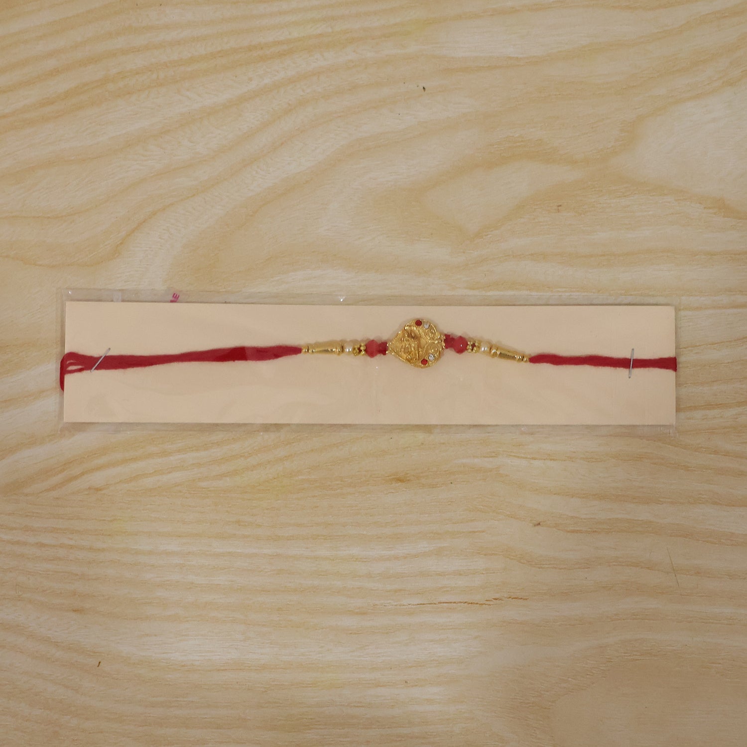 Golden Ganesha Oval Rakhi with Red Crystal Beads