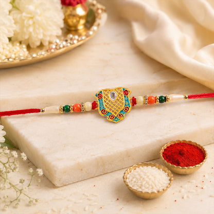 Designer enamel gold tone Rakhi with red thread