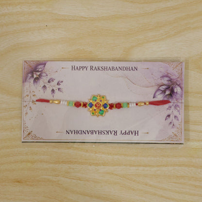 The colorful lotus and Om design, with red, green, and white beads on a red thread, is packaged on a decorative card with