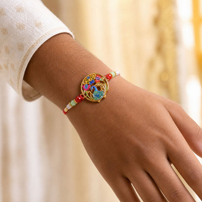 A person's wrist wears a colorful peacock and floral thread bracelet with red, green, and white beads.