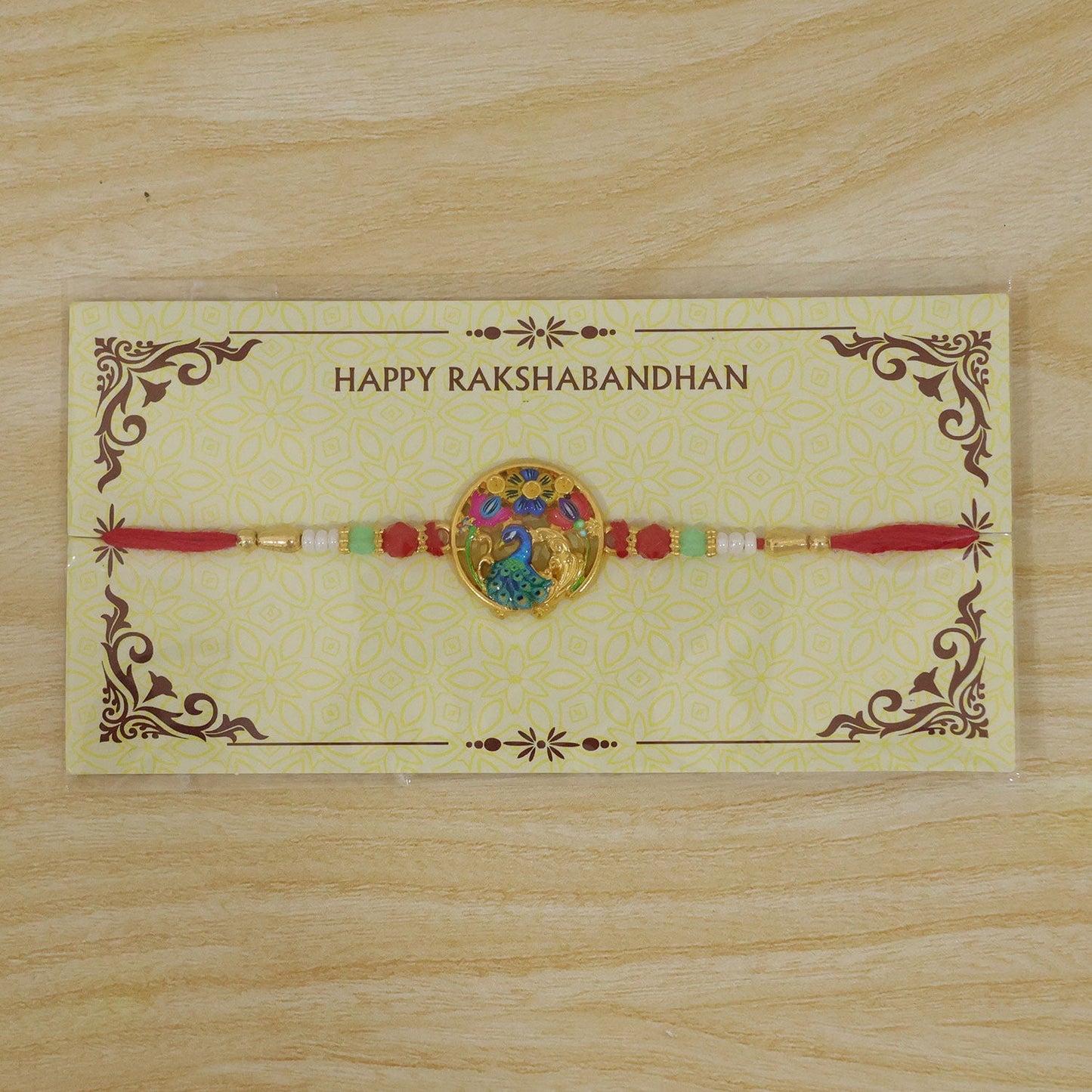 A red thread bracelet with a colorful peacock and floral design is presented on a yellow