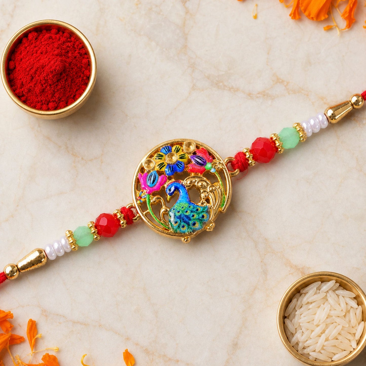 A colorful peacock and floral thread bracelet with red, green, and white beads is displayed on a light marble surface with
