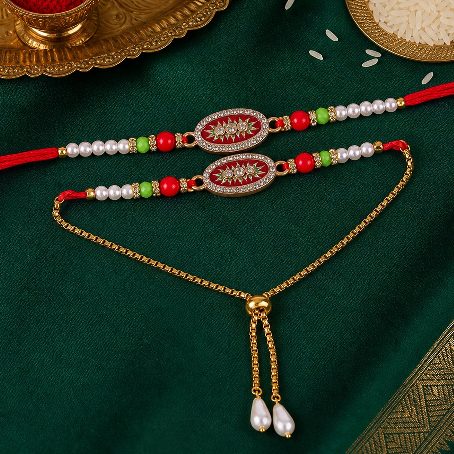 Two red and gold beaded bracelets with oval centers and pearl accents are displayed on a dark green fabric with a gold