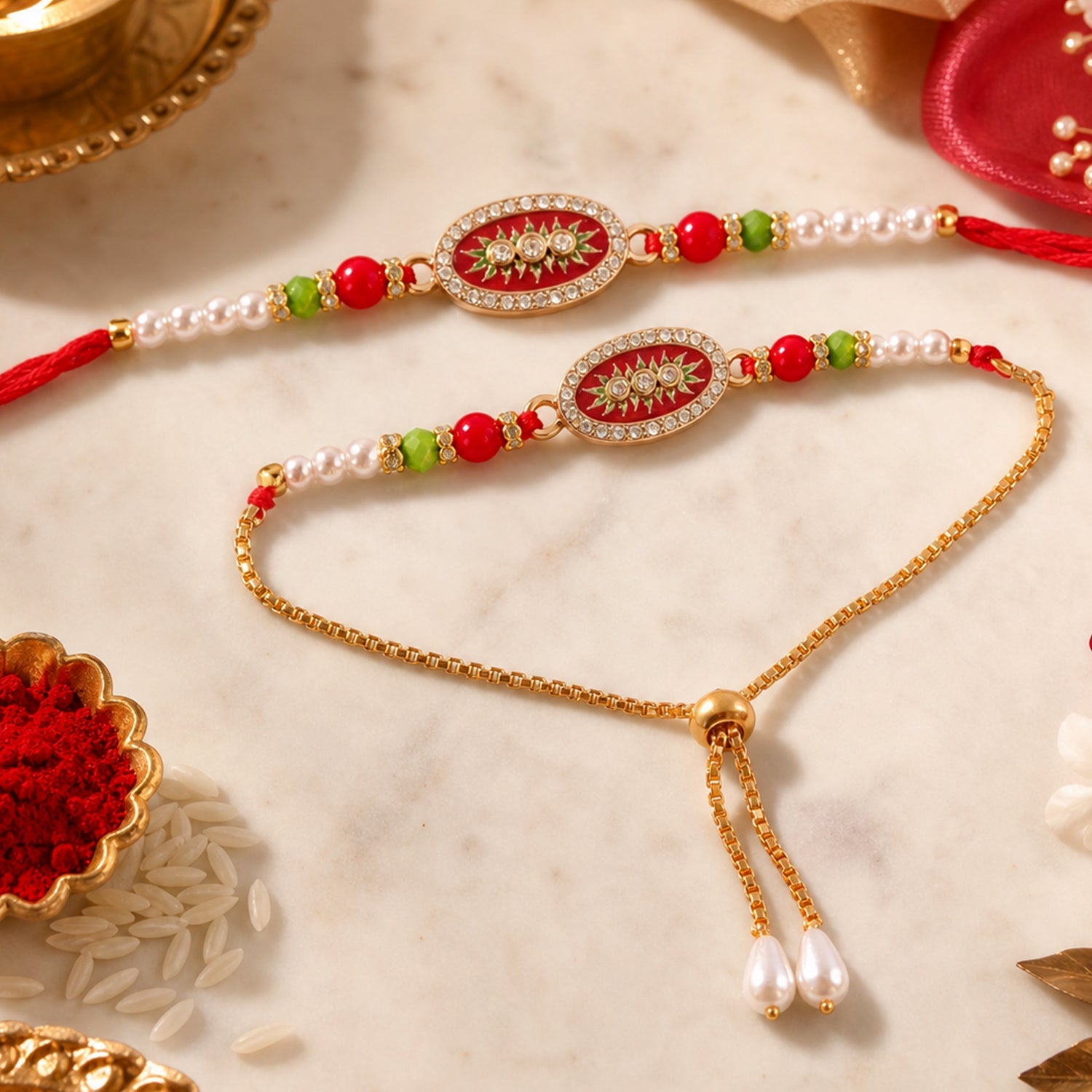 Two ornate red and gold beaded bracelets with oval centers and pearl accents rest on a white marble surface with rice and