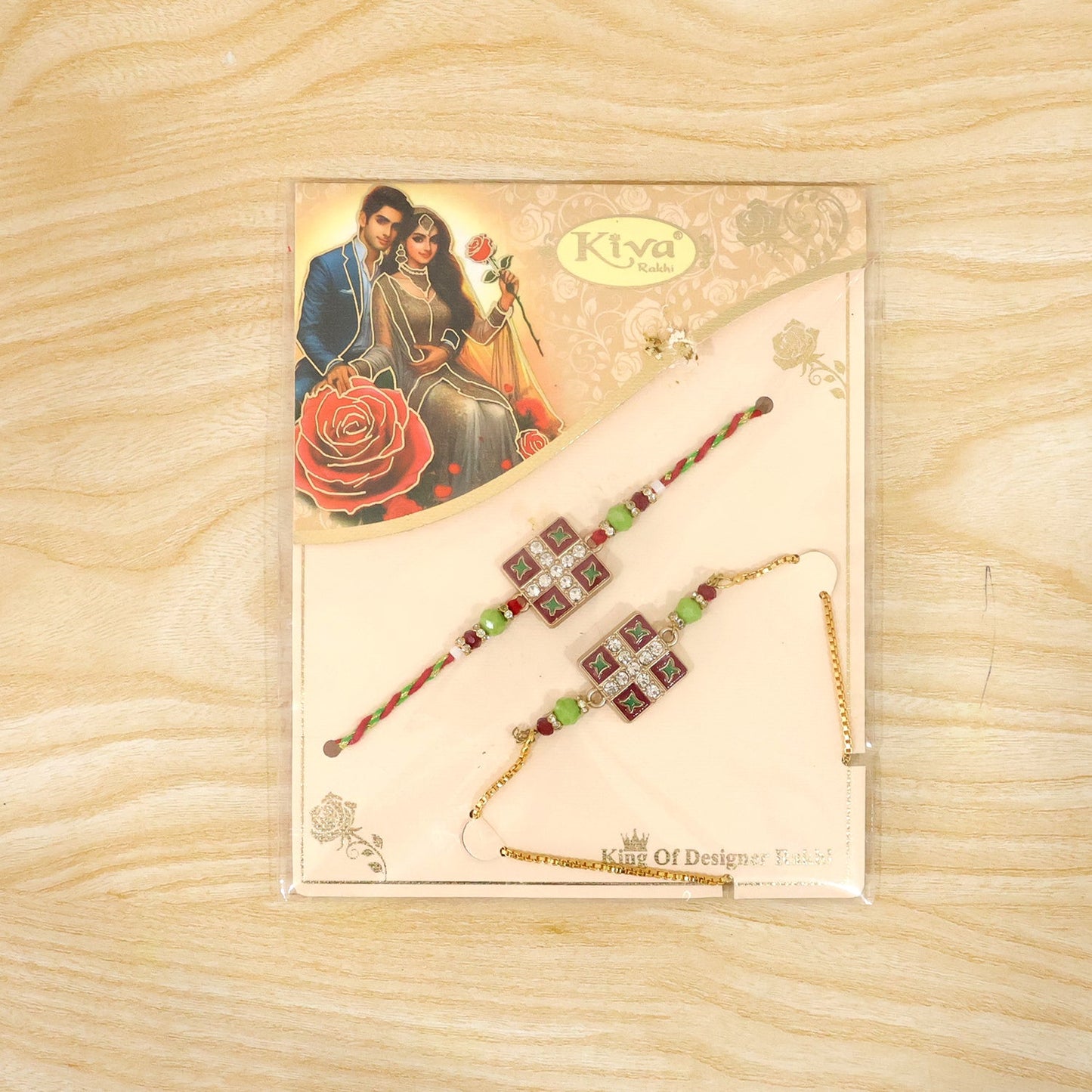 A pair of red and green beaded bracelets with square floral centers, one on a braided string and the other on a gold chain,