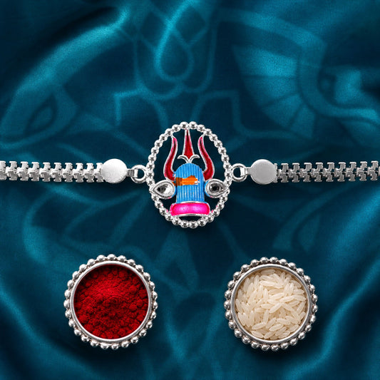 A silver chain bracelet with a colorful Shiva lingam charm, flanked by two small bowls of red powder and white rice, on a