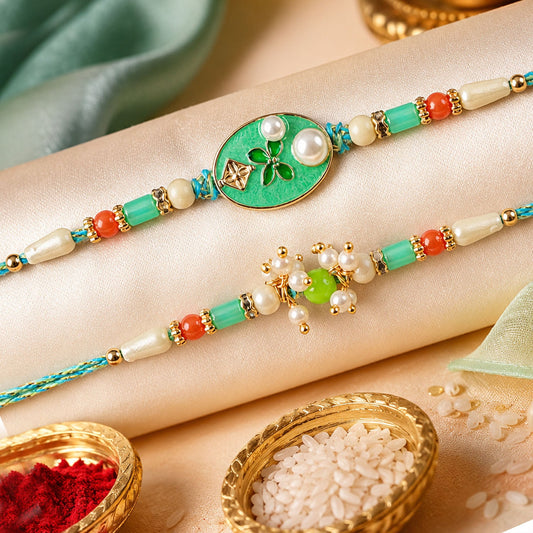 Two green, gold, and pearl bracelets with red beads are displayed on a satin cloth with rice and red powder in gold bowls.