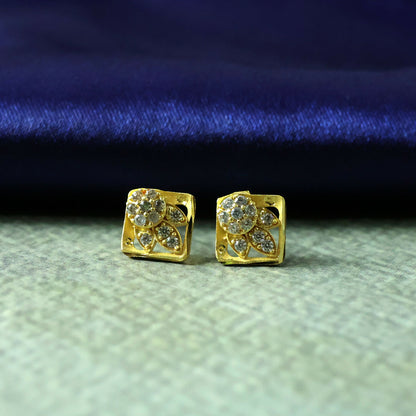Pair of gold floral stud earrings with stone accents resting on a jewelry box
