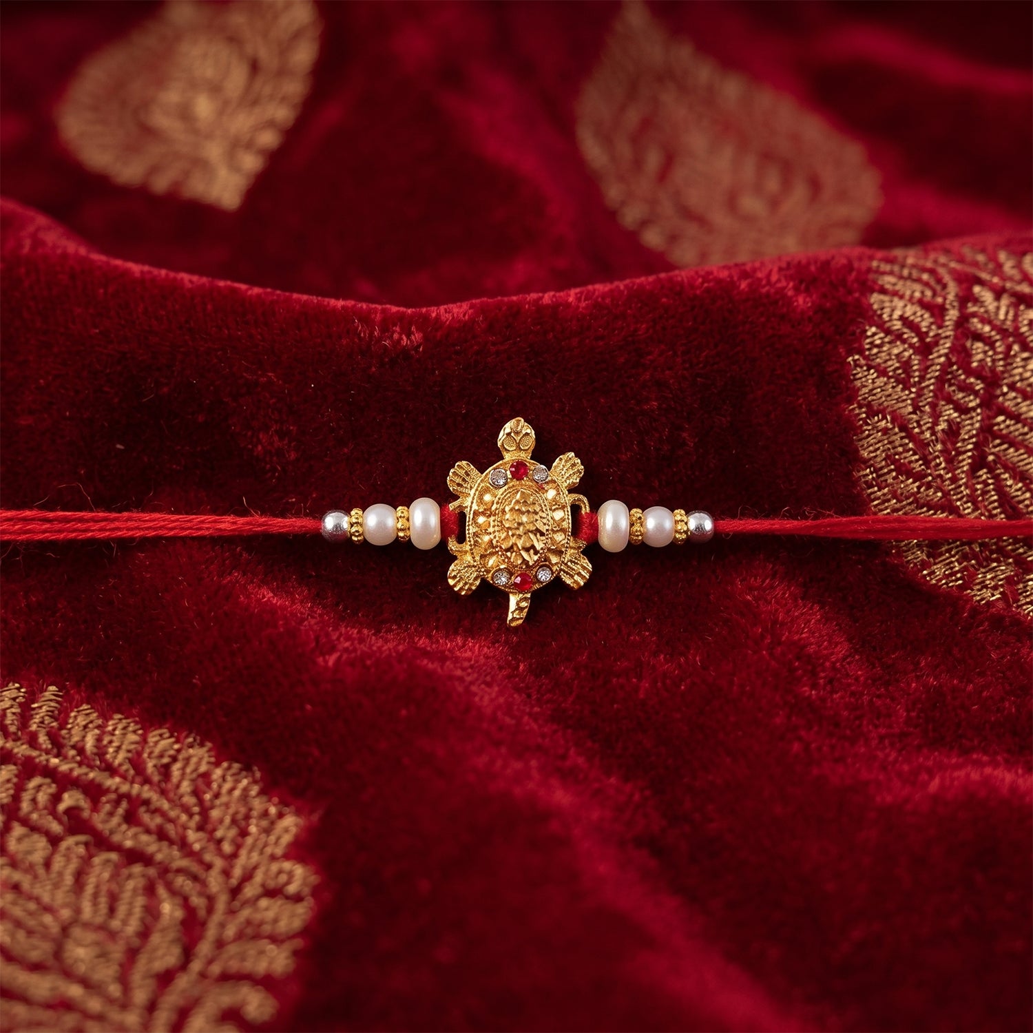 Gold Turtle Charm Rakhi with Pearl Sides and Red Mauli Thread