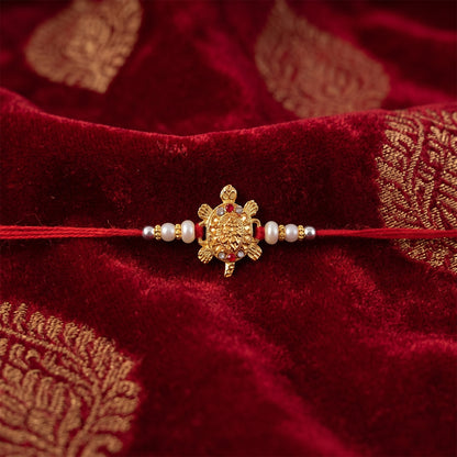 Gold Turtle Charm Rakhi with Pearl Sides and Red Mauli Thread