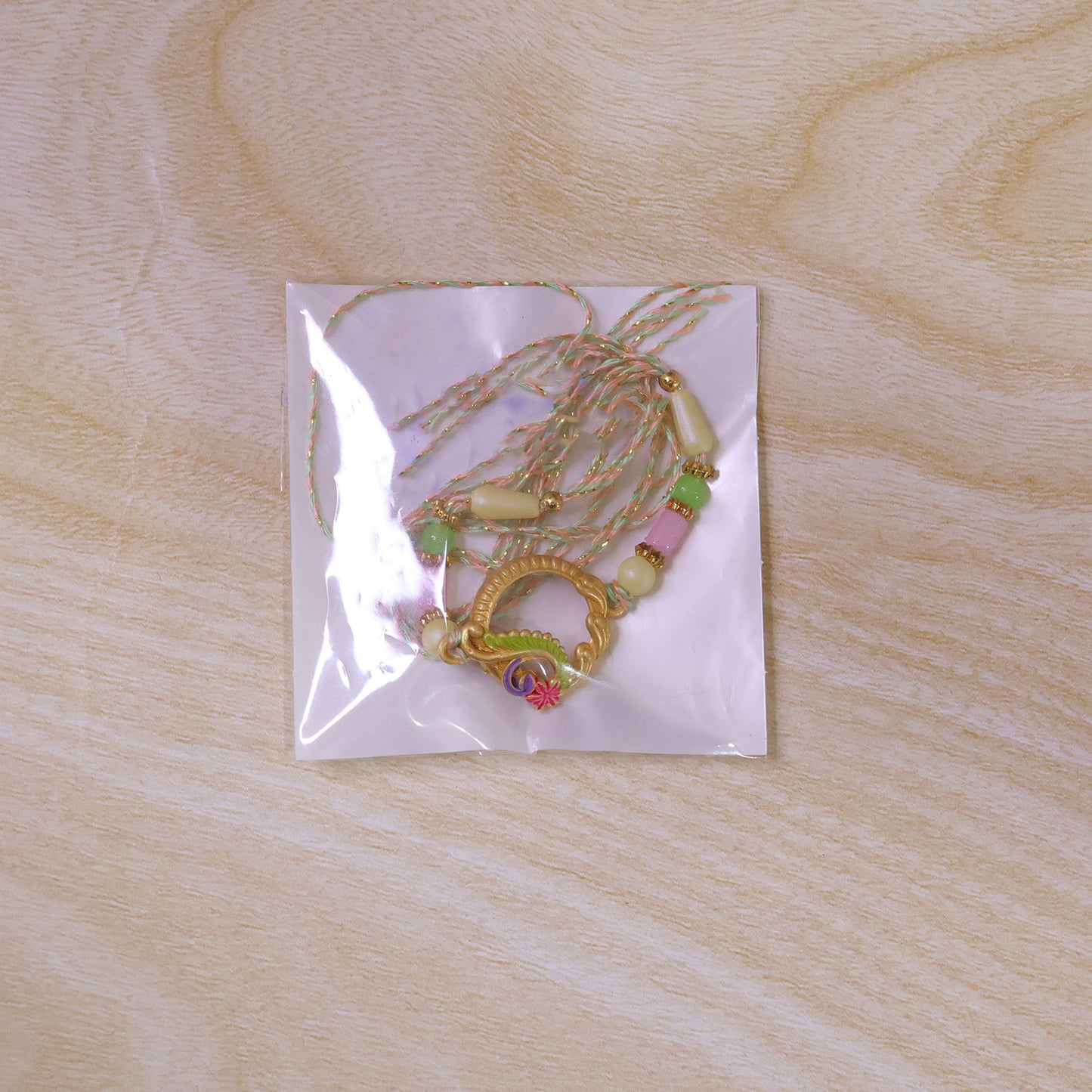 Golden Circular Rakhi with Pink Green Beads and Refined Festive Brother Gift Appeal