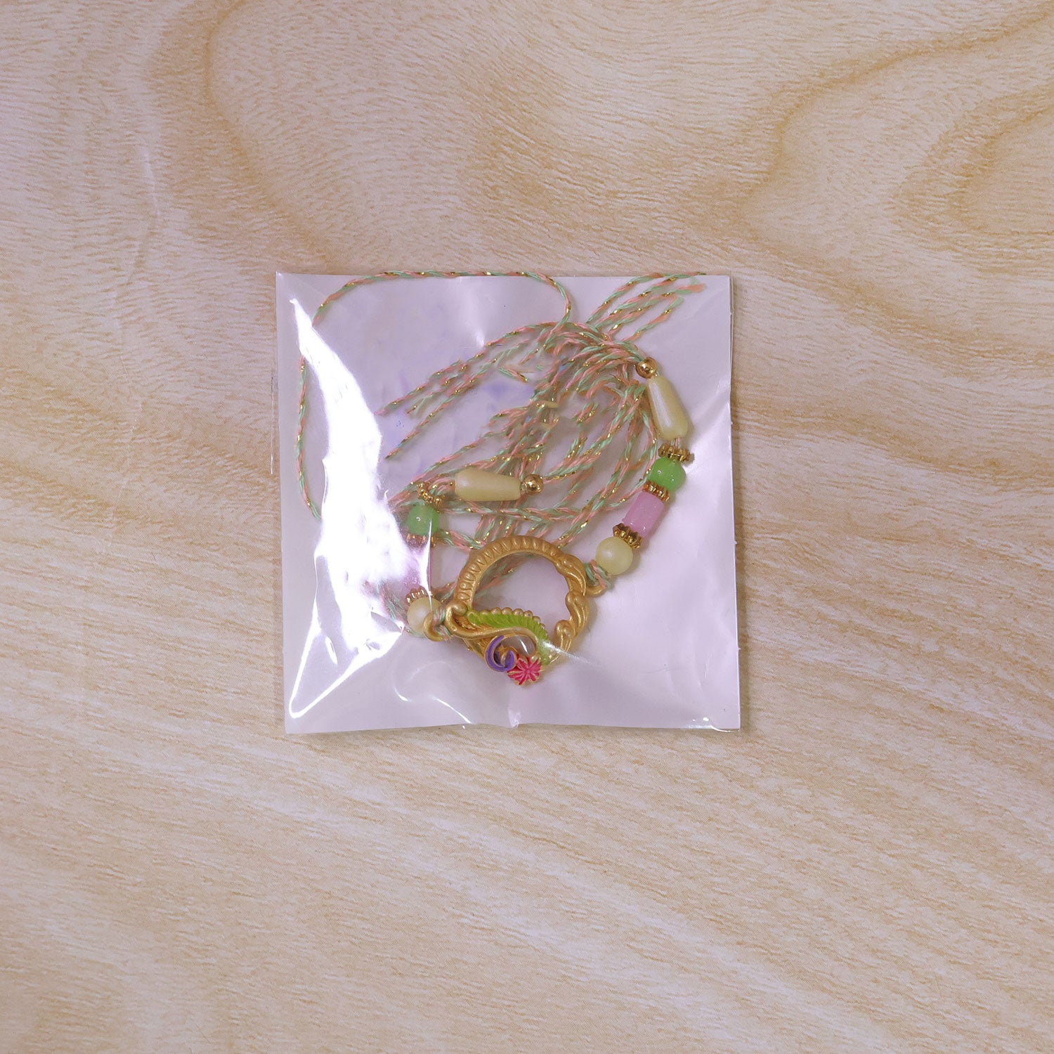 Golden Circular Rakhi with Pink Green Beads and Refined Festive Brother Gift Appeal
