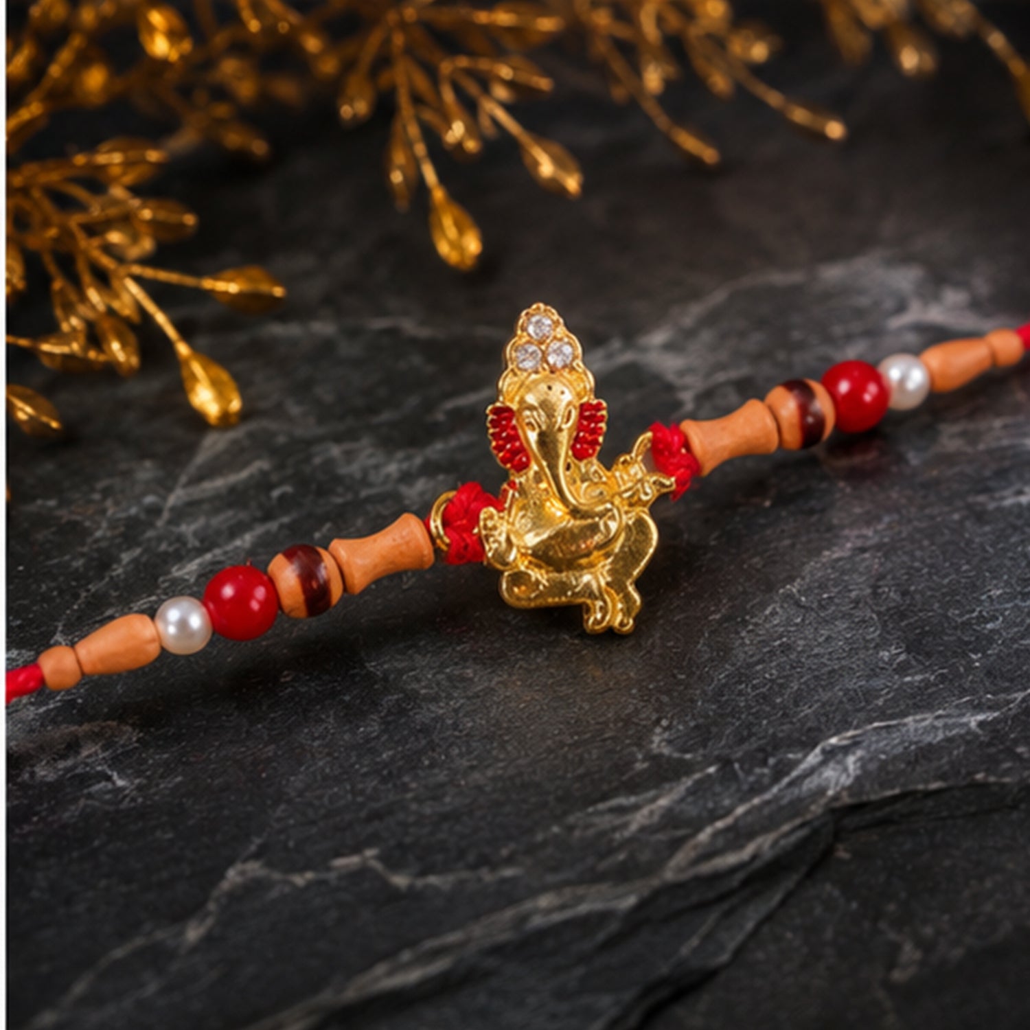 Golden Ganesha Rakhi with Peach Beads and Pearl Accents