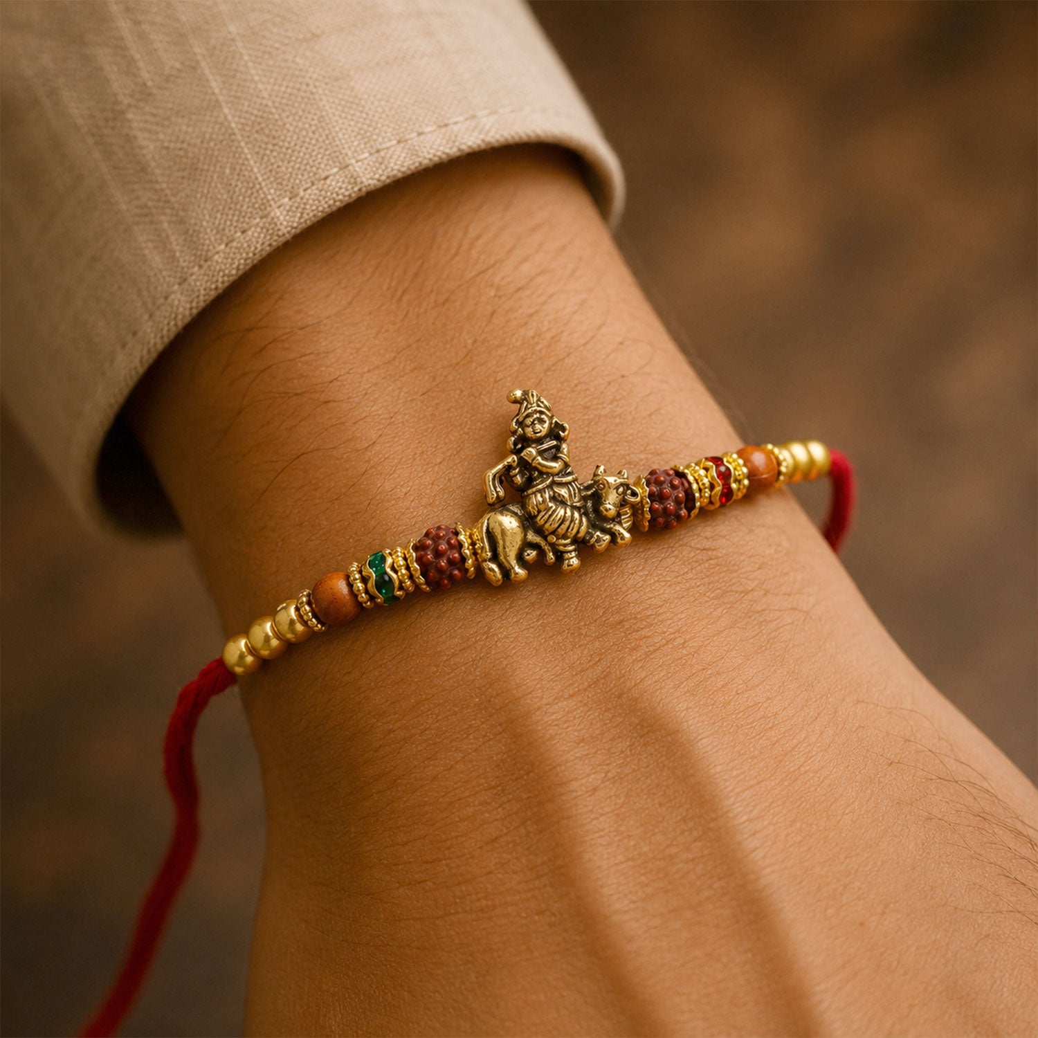Bal Krishna Golden Devotional Rakhi with Idol Centre, Red Beads and Pearl Accents