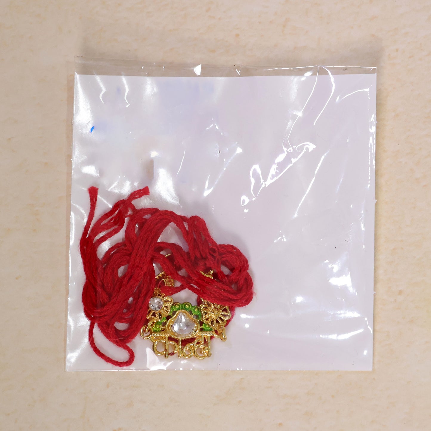 Gold-Toned Kanha Rakhi with Kundan-Style Stone, Green Enamel, Crystal Accents & Red Thread