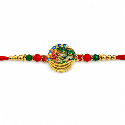 A vibrant Meenakari peacock and Ganesha circular dial, with red, green, and blue enamel, is centered on a red thread with