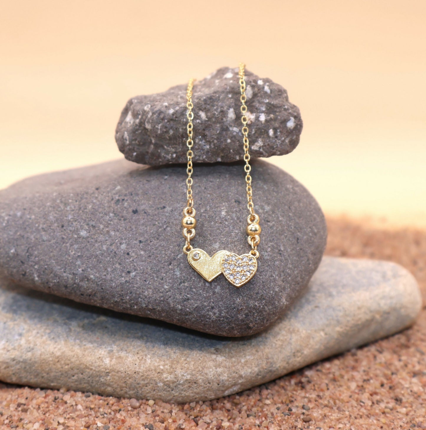 Close-up of sparkling Cubic Zirconia stones on gold plated double heart pendant necklace