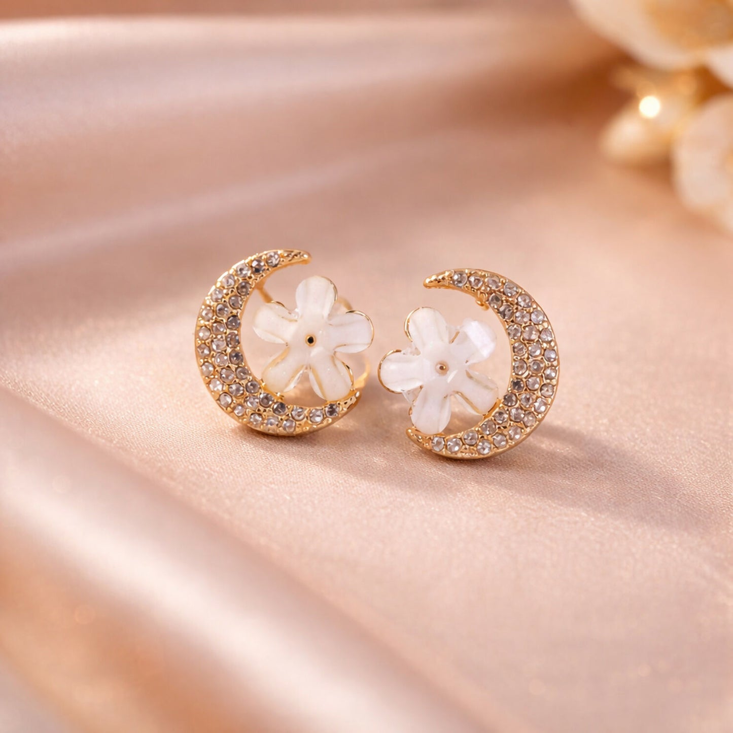 Close-up of gold moon and flower crystal stud earrings