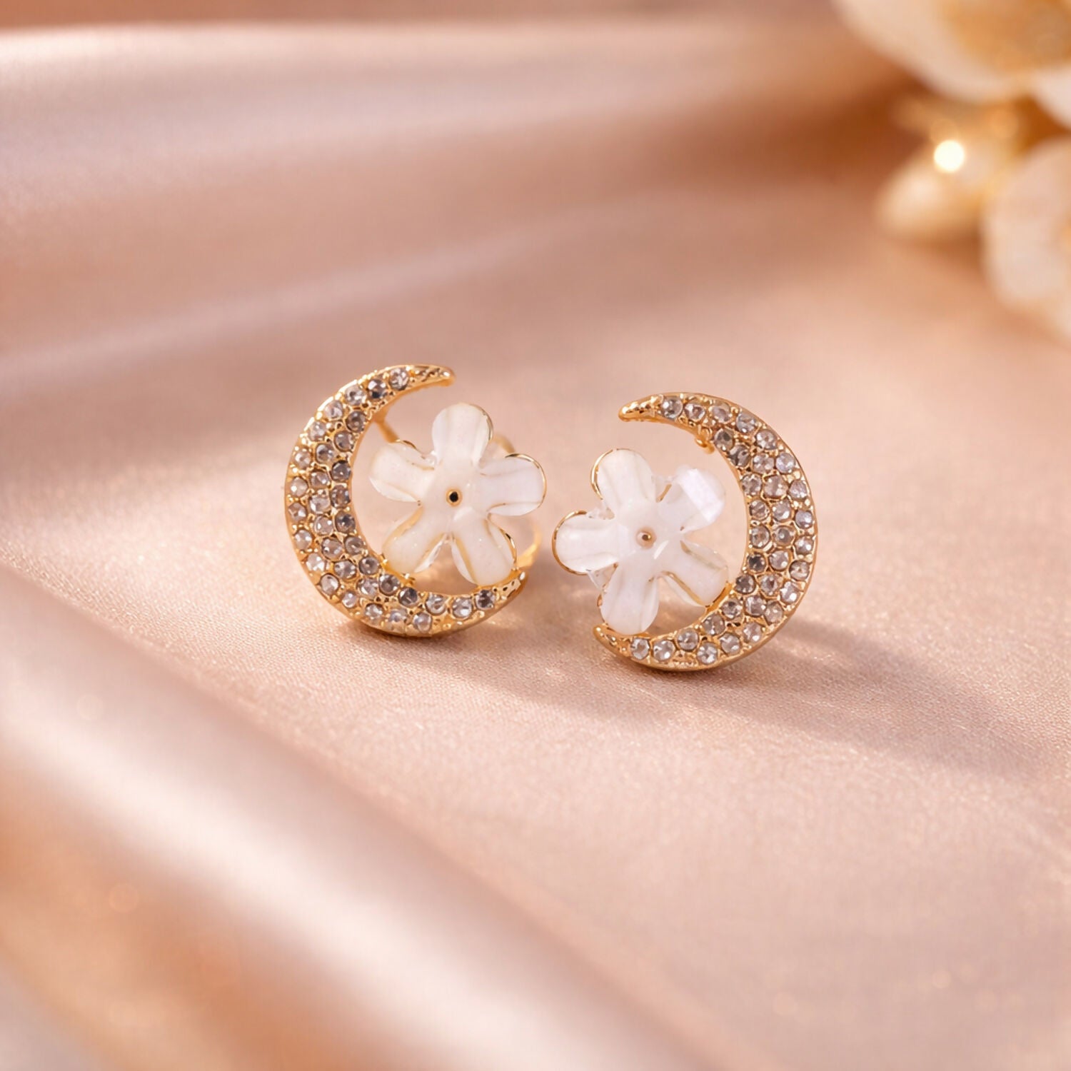 Close-up of gold moon and flower crystal stud earrings