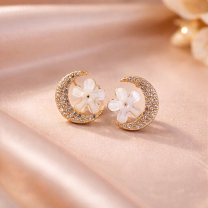 Close-up of gold moon and flower crystal stud earrings