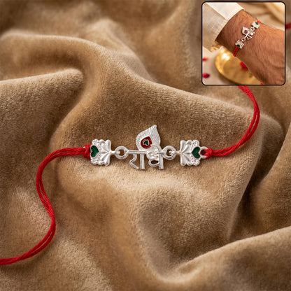 Silver Radhe Morpich Text Rakhi with Green Stones and Red Thread